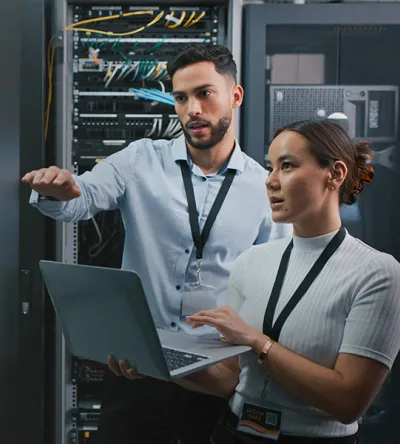 Technology professionals working in a server room surrounded by servers.